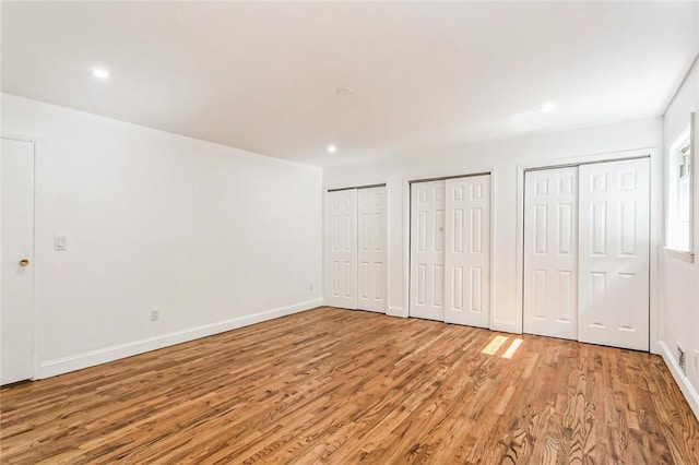 unfurnished bedroom featuring light hardwood / wood-style flooring and multiple closets