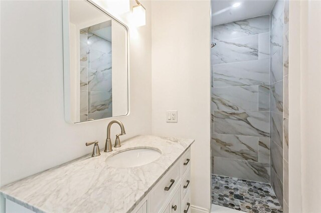 bathroom with a tile shower and vanity