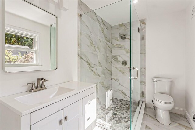 bathroom featuring vanity, a shower with shower door, and toilet