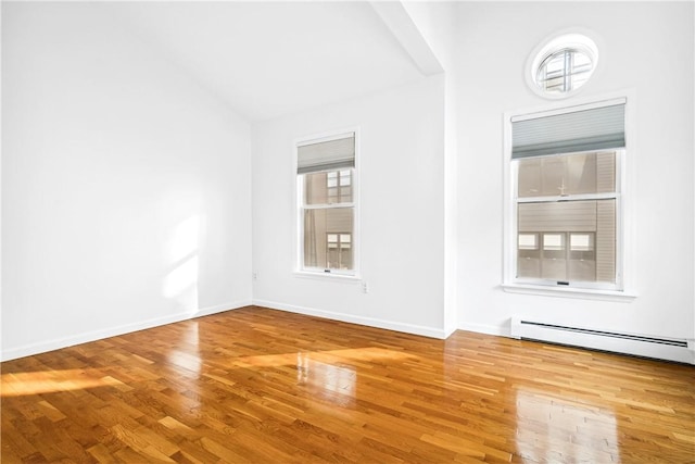 unfurnished room with a baseboard radiator, vaulted ceiling, and hardwood / wood-style flooring