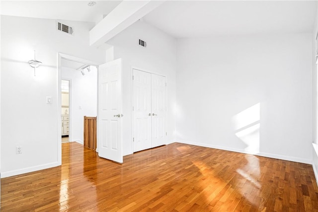 unfurnished bedroom featuring hardwood / wood-style flooring, high vaulted ceiling, and a closet