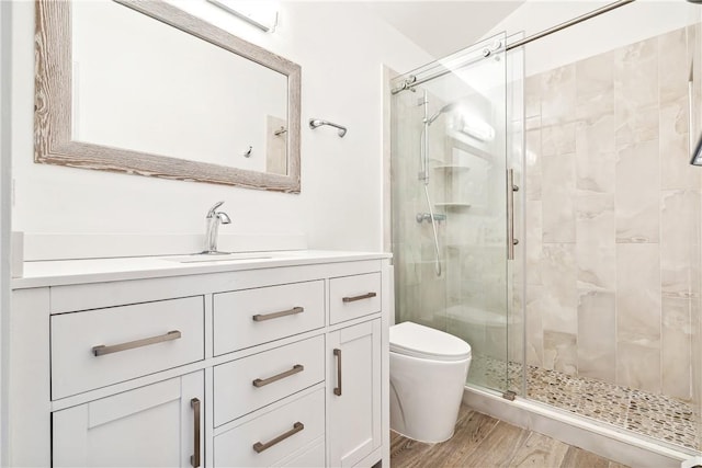 bathroom with hardwood / wood-style floors, vanity, toilet, and a shower with door