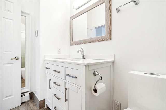 bathroom with baseboard heating, vanity, wood-type flooring, and toilet