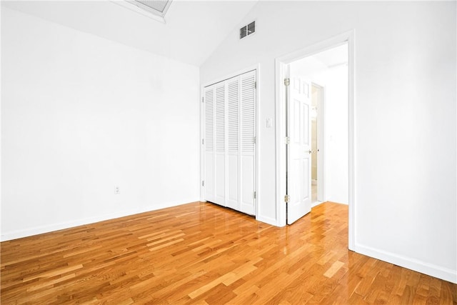 unfurnished bedroom featuring light hardwood / wood-style floors, a closet, and lofted ceiling