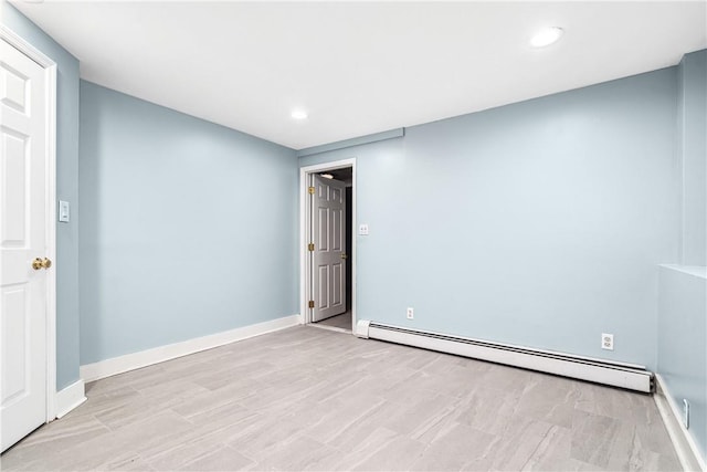 empty room featuring a baseboard radiator and light hardwood / wood-style flooring