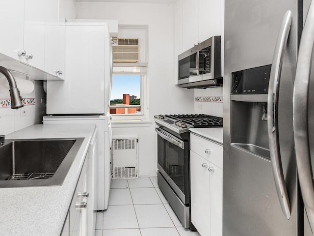 kitchen with sink, white cabinets, light tile patterned floors, and appliances with stainless steel finishes