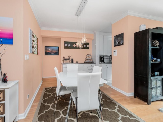 dining area featuring light hardwood / wood-style floors, an inviting chandelier, and ornamental molding