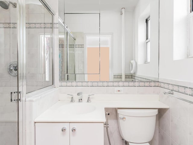 bathroom with an enclosed shower, vanity, toilet, and tile walls