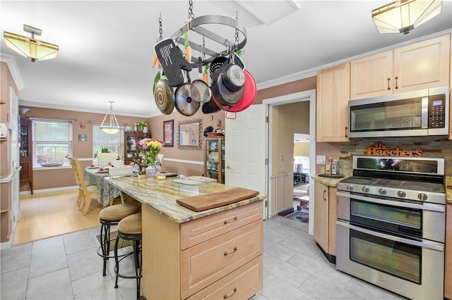 kitchen featuring light stone counters, ornamental molding, stainless steel appliances, a kitchen island, and a breakfast bar area