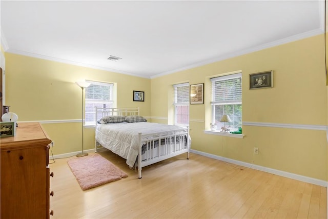 bedroom featuring crown molding, light hardwood / wood-style flooring, and multiple windows