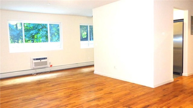 empty room with a baseboard heating unit, a wall unit AC, light hardwood / wood-style floors, and a healthy amount of sunlight