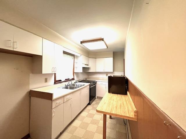 kitchen with black / electric stove, white cabinetry, and sink