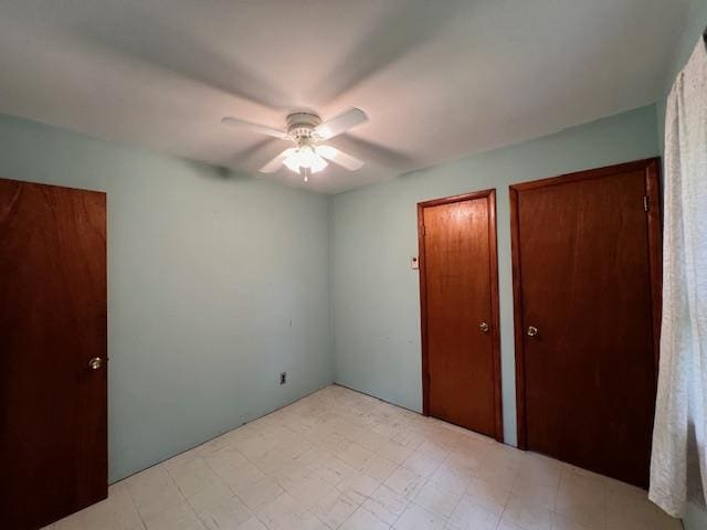 unfurnished bedroom with two closets and ceiling fan