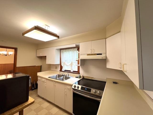 kitchen with white cabinetry, sink, stainless steel range with electric stovetop, and a notable chandelier