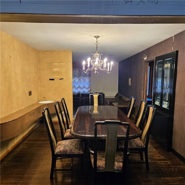 dining space featuring wooden walls, dark hardwood / wood-style floors, and a notable chandelier