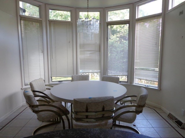 tiled dining space featuring plenty of natural light and a chandelier