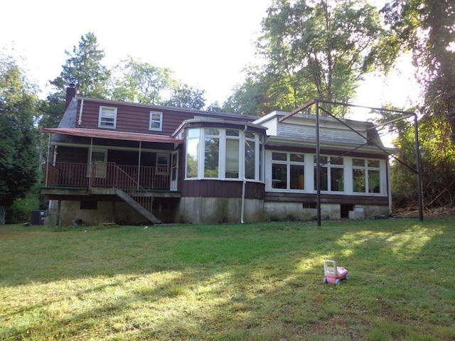 rear view of property with a yard, central air condition unit, and a sunroom