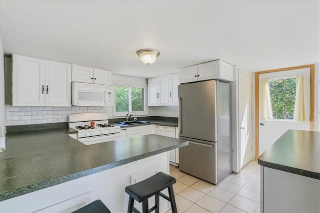 kitchen featuring white cabinetry, light tile patterned flooring, white appliances, and a wealth of natural light