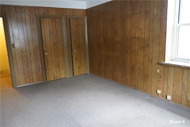 carpeted spare room featuring wooden walls