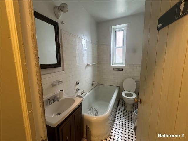 bathroom with vanity, tile walls, tile patterned flooring, toilet, and a tub