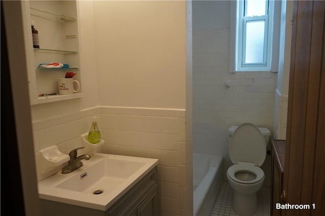 bathroom featuring tile patterned floors, a bathtub, vanity, tile walls, and toilet