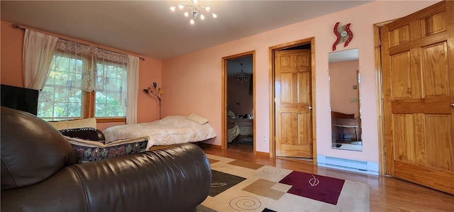 bedroom with light hardwood / wood-style floors, baseboard heating, and a chandelier