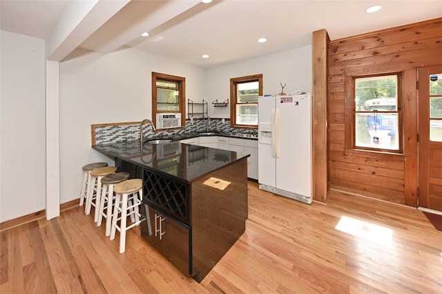 kitchen featuring kitchen peninsula, a wealth of natural light, light hardwood / wood-style floors, and white refrigerator with ice dispenser