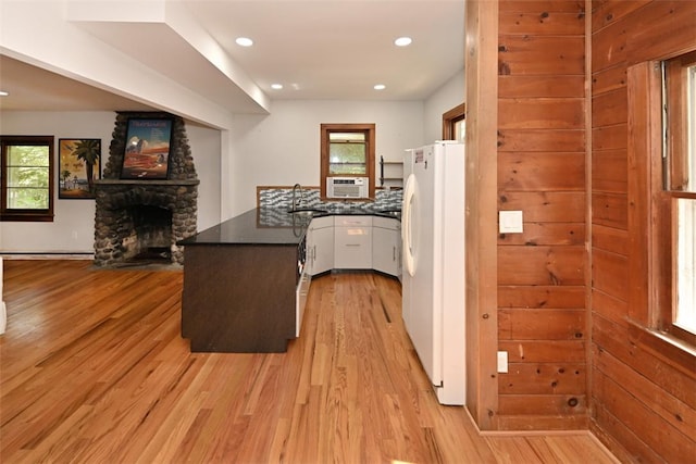 kitchen featuring kitchen peninsula, light wood-type flooring, sink, white refrigerator, and a fireplace