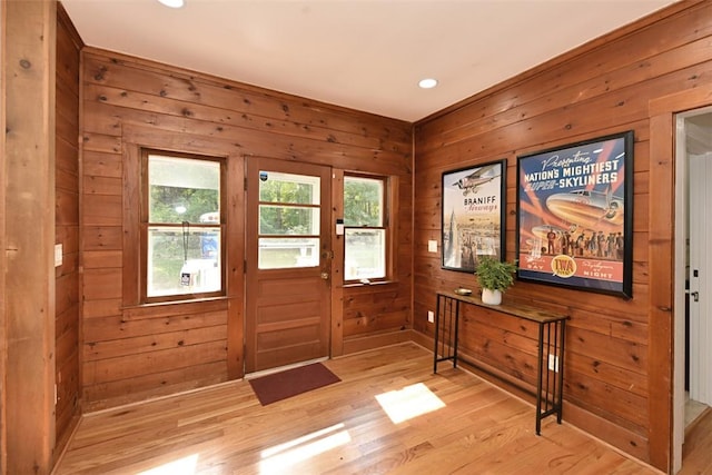 entryway with light hardwood / wood-style floors and wooden walls