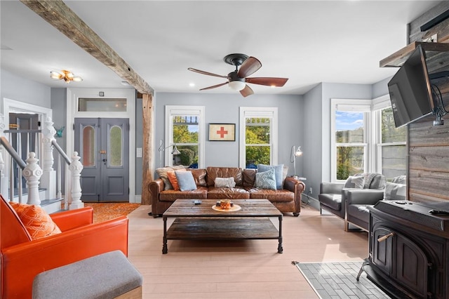 living room featuring plenty of natural light, light hardwood / wood-style floors, beam ceiling, and ceiling fan