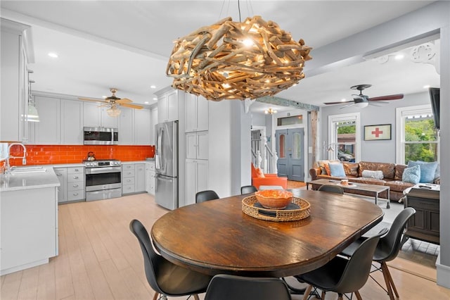 dining area with light wood-type flooring, ceiling fan, and sink