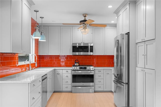 kitchen featuring ceiling fan, sink, stainless steel appliances, light hardwood / wood-style flooring, and pendant lighting