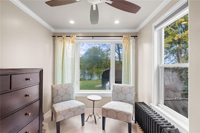 living area featuring radiator heating unit, light hardwood / wood-style flooring, a healthy amount of sunlight, and crown molding