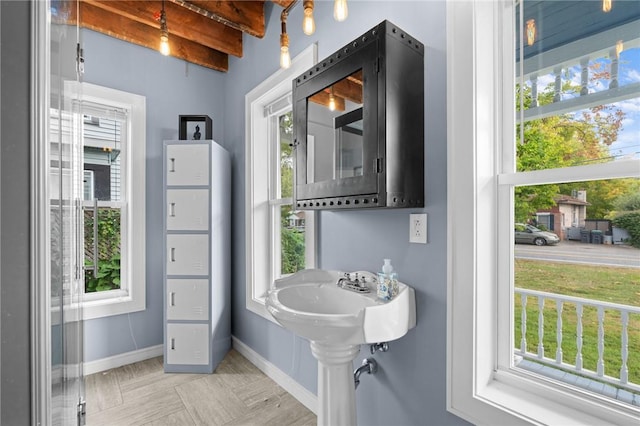 bathroom featuring beam ceiling and a wealth of natural light