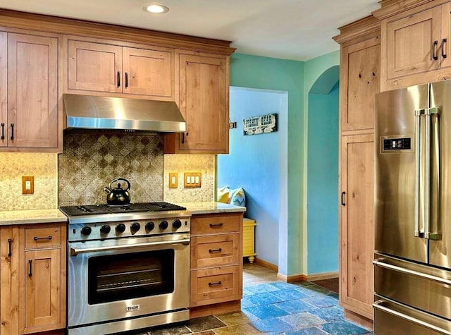 kitchen with premium appliances, decorative backsplash, and light stone countertops