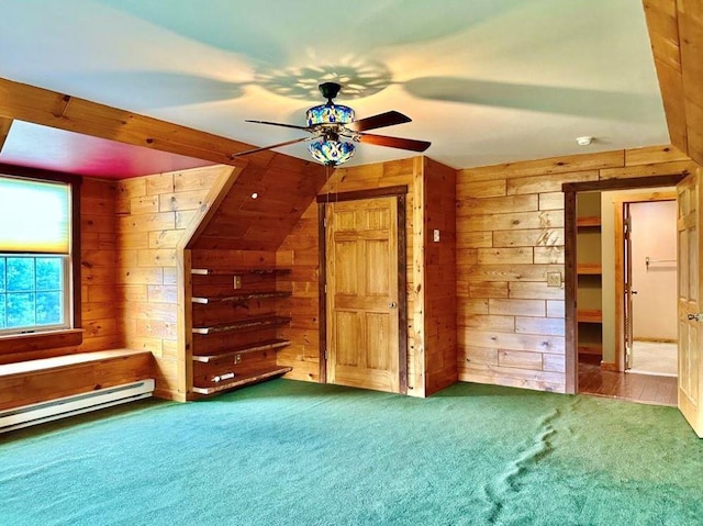 additional living space with a baseboard heating unit, carpet floors, ceiling fan, and wooden walls