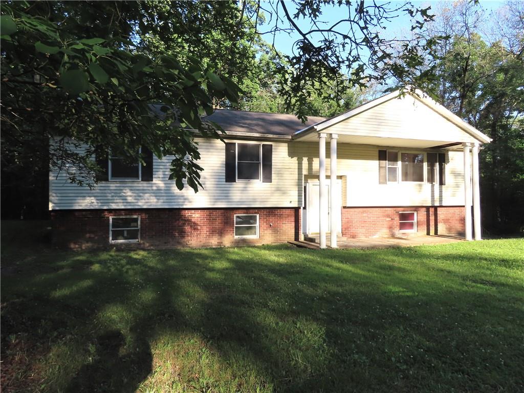 raised ranch featuring covered porch and a front yard