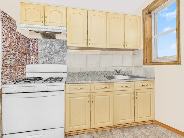 kitchen featuring tasteful backsplash, light brown cabinetry, sink, and white gas range oven