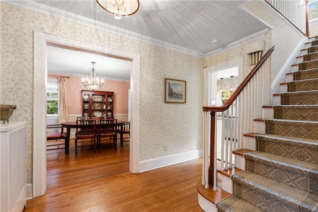 staircase with ornamental molding, a chandelier, and hardwood / wood-style flooring