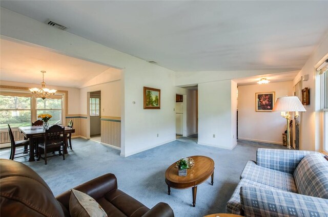 carpeted living room featuring a chandelier and vaulted ceiling