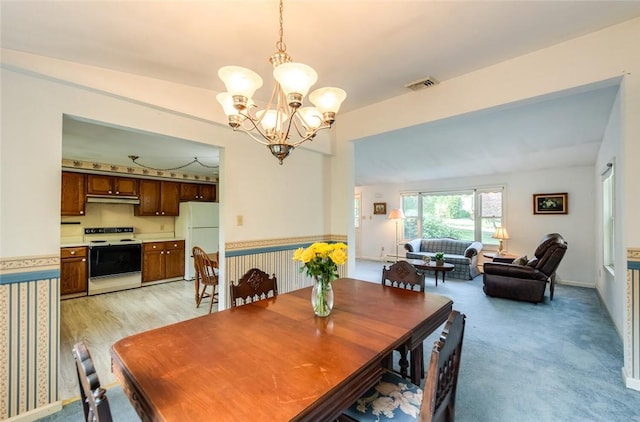 dining space with a notable chandelier and light carpet