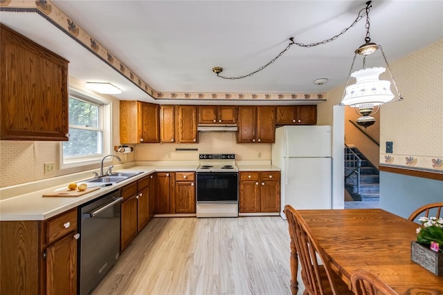 kitchen with sink, hanging light fixtures, white appliances, and light wood-type flooring