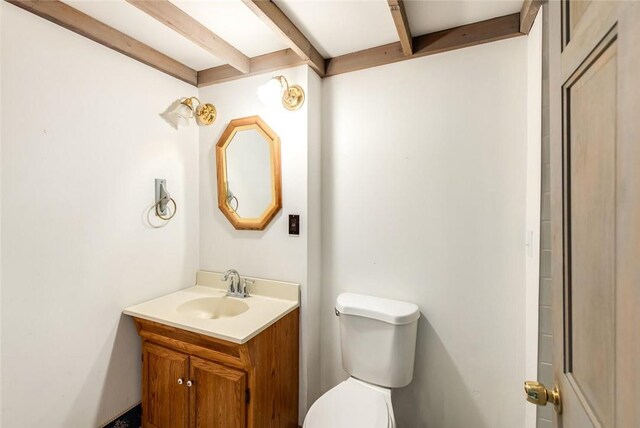 bathroom featuring beamed ceiling, vanity, and toilet