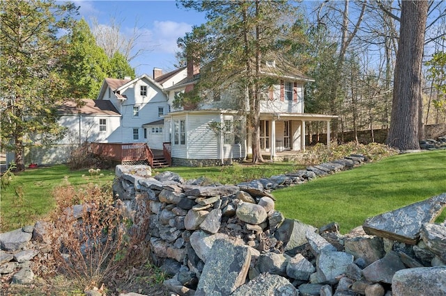 rear view of property featuring a yard and a wooden deck