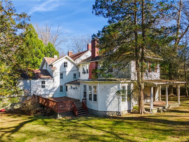 back of property featuring a wooden deck and a yard