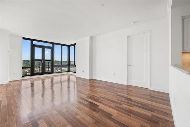 spare room with hardwood / wood-style flooring, a wall of windows, and crown molding