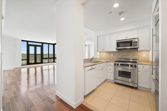 kitchen featuring backsplash, white cabinets, sink, light wood-type flooring, and appliances with stainless steel finishes