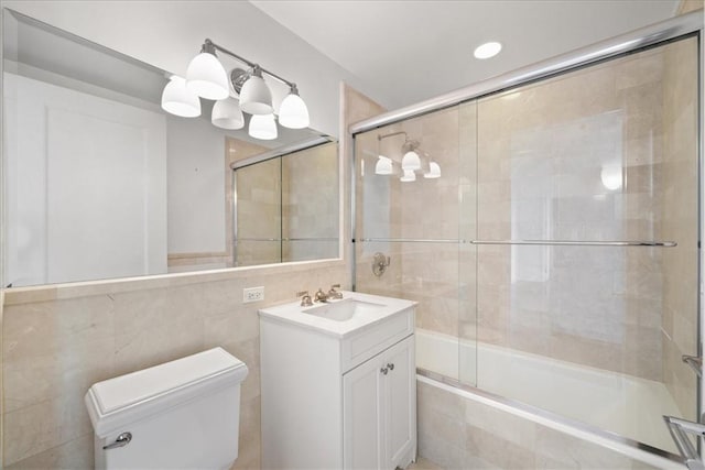 full bathroom with toilet, combined bath / shower with glass door, tile walls, and vanity