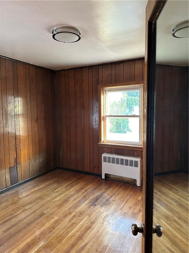 unfurnished room with hardwood / wood-style floors and wood walls