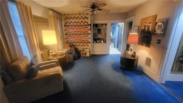 sitting room featuring dark carpet and ceiling fan